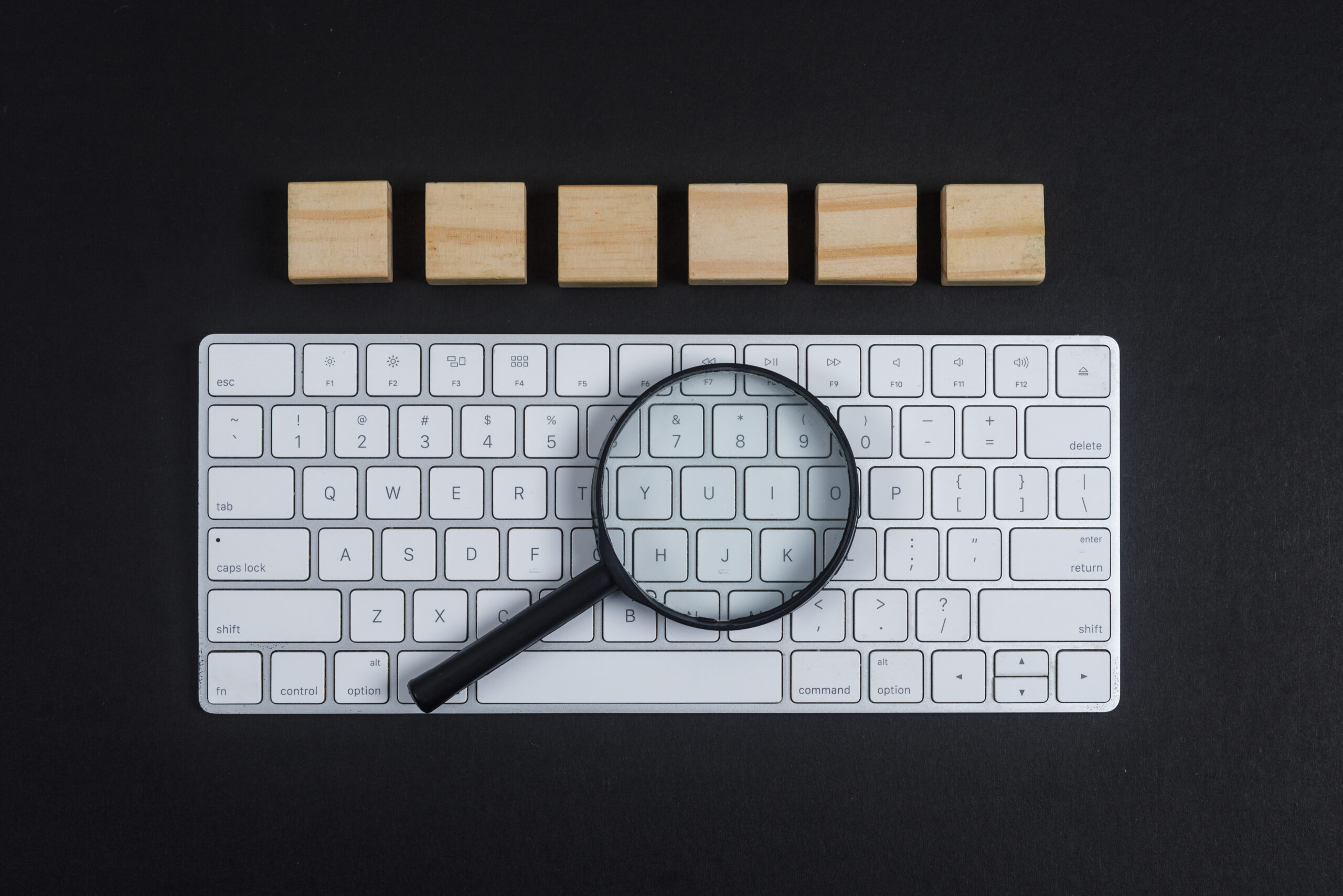 Conceptual of research with keyboard, magnifier, wooden cubes on black desk background flat lay. horizontal image